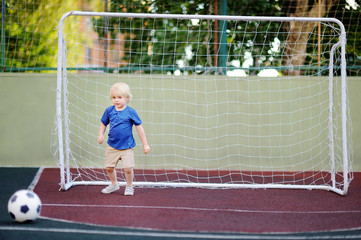 Little boy having fun playing a soccer/football game on summer day