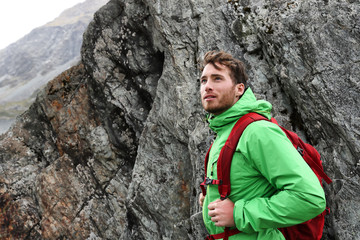 Hiker - man hiking in mountains. Adventure outdoor lifestyle. Male hiker looking to the side...