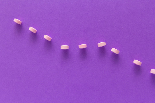 Heap of pills spreaded over color table. Group pink tablets.