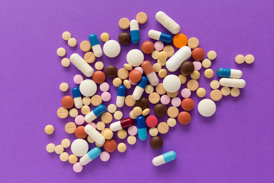 Heap of pills spreaded over color table. Group of assorted colorful tablets.