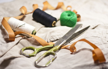 Fototapeta na wymiar scissors with ruler and threads on cotton textile