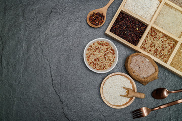 Brown rice, Black Jasmine rice, Red jasmine rice and Riceberry in boxes and bowl on black desk. Free space for your text.