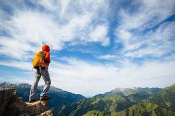 Successful woman backpacker enjoy the view on top of mountain rock .