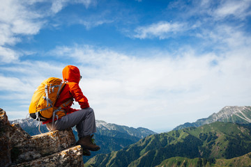 Successful woman backpacker enjoy the view on top of mountain rock
