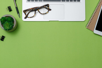 Workspace home office on green desk with laptop. Top view with copy space, flat lay.