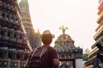 Young Asian traveling backpacker in Wat Pho with India inspired temple in Bangkok, Thailand