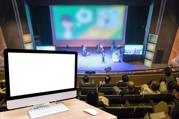 Computer set showing the white screen over the Abstract blurred photo of conference hall or seminar room with attende background, business and education concept