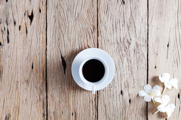 white coffee cup and frangipani flowers on old wooden table background.