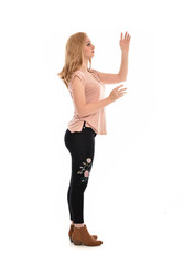 full length portrait of a girl wearing pink shirt and black floral pants. standing pose, isolated on white background.