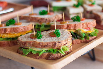 Canape  sandwiches with toothpicks and fresh vegetables on wooden board