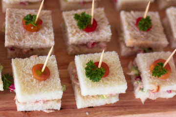 Canape  sandwiches with toothpicks and fresh vegetables on wooden board