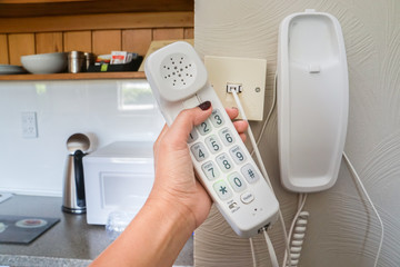 close up woman hold landline telephone at the house wall