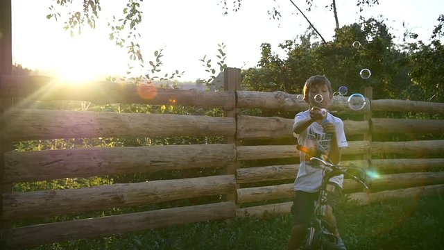 Boy Blowing Soap Bubbles At Sunset