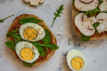 Ciabatta for breakfast. Sandwiches with arugula, egg, mushrooms, cucumbers and tomatoes
