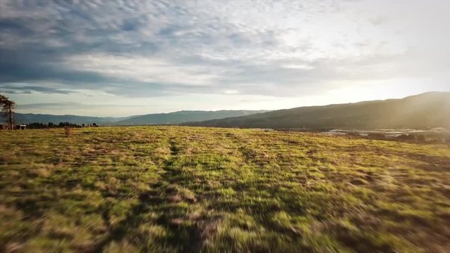 Drone racing quad copter flying over hills at sunset.