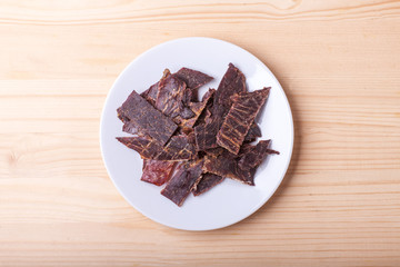dry beef meat slices in white dish on wooden table