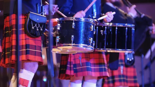 Traditional scottish band musicians singing with bagpipes and drums on the stage