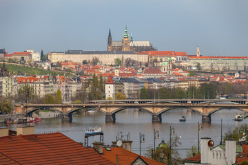 Obraz premium View of Vltava river in Prague and Charles bridge and the Castle over red roofs, Czech Republic