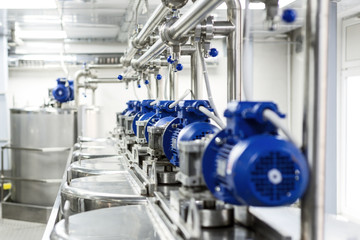 Rows of blue electric motors on tanks for mixing liquids.