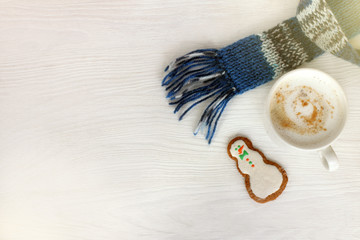 winter coffee break with mood/ white mug with cappuccino in blue scarf and ginger snowman on table...