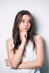 Fototapeta premium portrait of the beautiful young woman on a white background. Thinks looking up