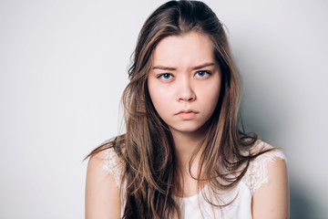 Close up isolated portrait of young annoyed angry woman. Young female in white T-shirt. Negative...