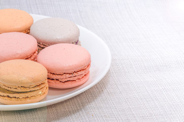 Delicious cake macaroons on plate on light background, close up