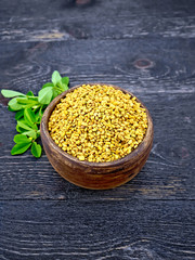 Fenugreek with green leaf in clay bowl on wooden board
