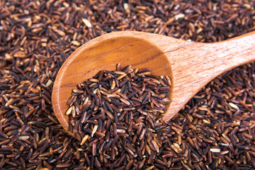 Brown rice with wooden spoon background