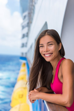 Happy travel woman on cruise vacation smiling at her Caribbean or Europe holidays ahead of her. Summer holiday. Asian girl enjoying ocean view of balcony of her luxury suite in the ship.