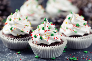 Chocolate cupcake decorated white cream and fir trees on a dark table. Christmas sweets. New year dessert
