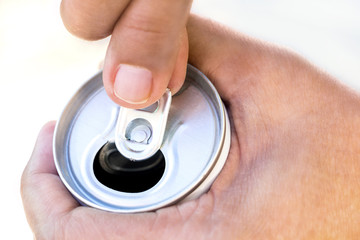 A hand opening a canned beverage.