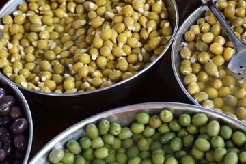 Olives of different varieties in large vats, top view, Spanish market