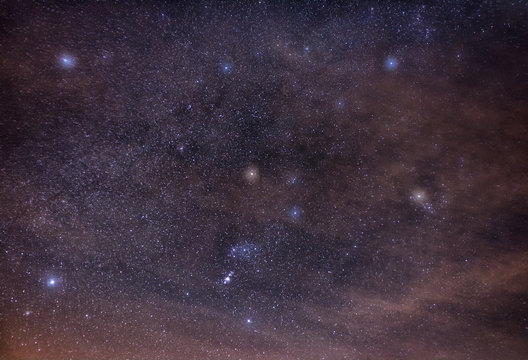 Constellations of Orion, Taurus, Auriga and Gemini in the starry night sky, shrouded in clouds