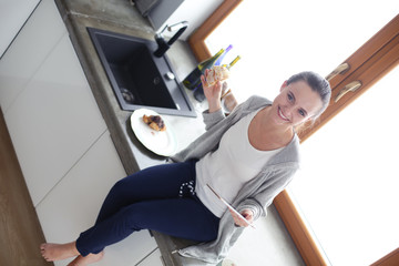 Obraz premium Beautiful young woman using a digital tablet in the kitchen.