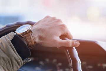 Men's hand with a wristwatch on the steering wheel