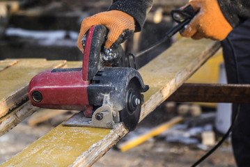 male hands with circular saw while workimg with wood