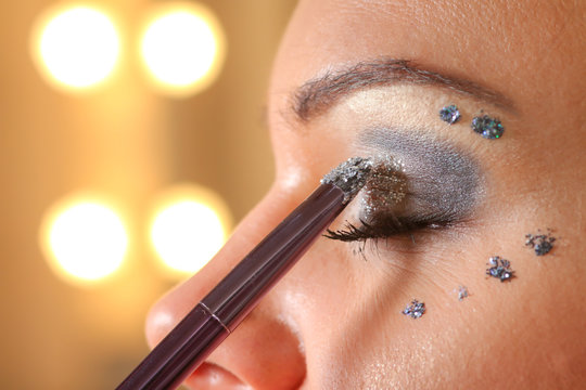 Woman applying mascara on her eyes by brush