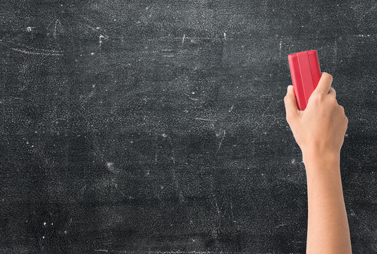 Hand holding brush erase on black chalkboard