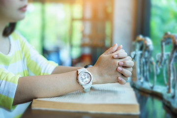 woman praying on holy bible in the morning. teenager hand with Bible praying,Hands folded in prayer on a Holy Bible in church concept for faith, spirituality and religion. victory concept for god.