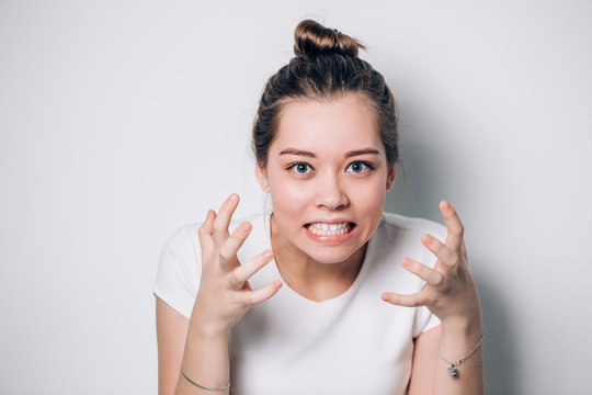 Close up isolated portrait of young annoyed angry woman holding hands in furious gesture. Young female in white T-shirt. Negative human emotions, face expressions. Film effect