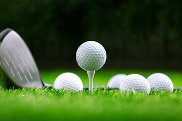 Golf balls and golf club on green grass