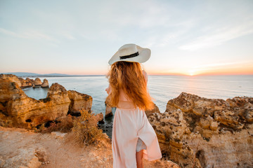 Woman enjoying great view on the rocky coastline during the sunrise in Lagos on the south of...