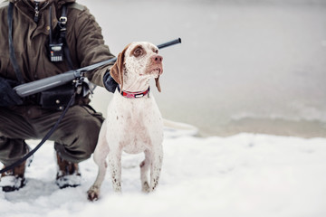 hunter and his Bourbonnais Pointing Dog by a river in the winter hunting season.