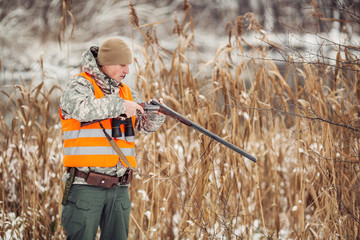 hunter loading rifle in a winter forest. Bushcraft, hunting and people concept