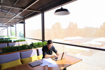 Freelance copywriter rewrite text on laptop at cafe table.
