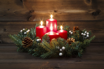 Fourth Advent - Decorated Advent wreath with four red burning candles on a wooden background