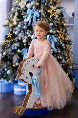 Merry Christmas celebration. Beautiful little girl in a amazing dress near the Christmas tree. Christmas miracles. Happy New Year