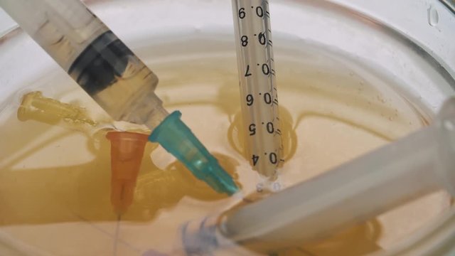 Medical syringe put in a glass bowl with drugs stands on the table 