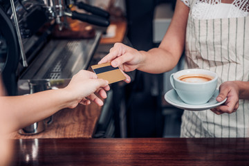 customer pay coffee drink with credit card to barista,Close up hand paid for to go coffee cup at counter bar in cafe,Food and drink business,billing payment.